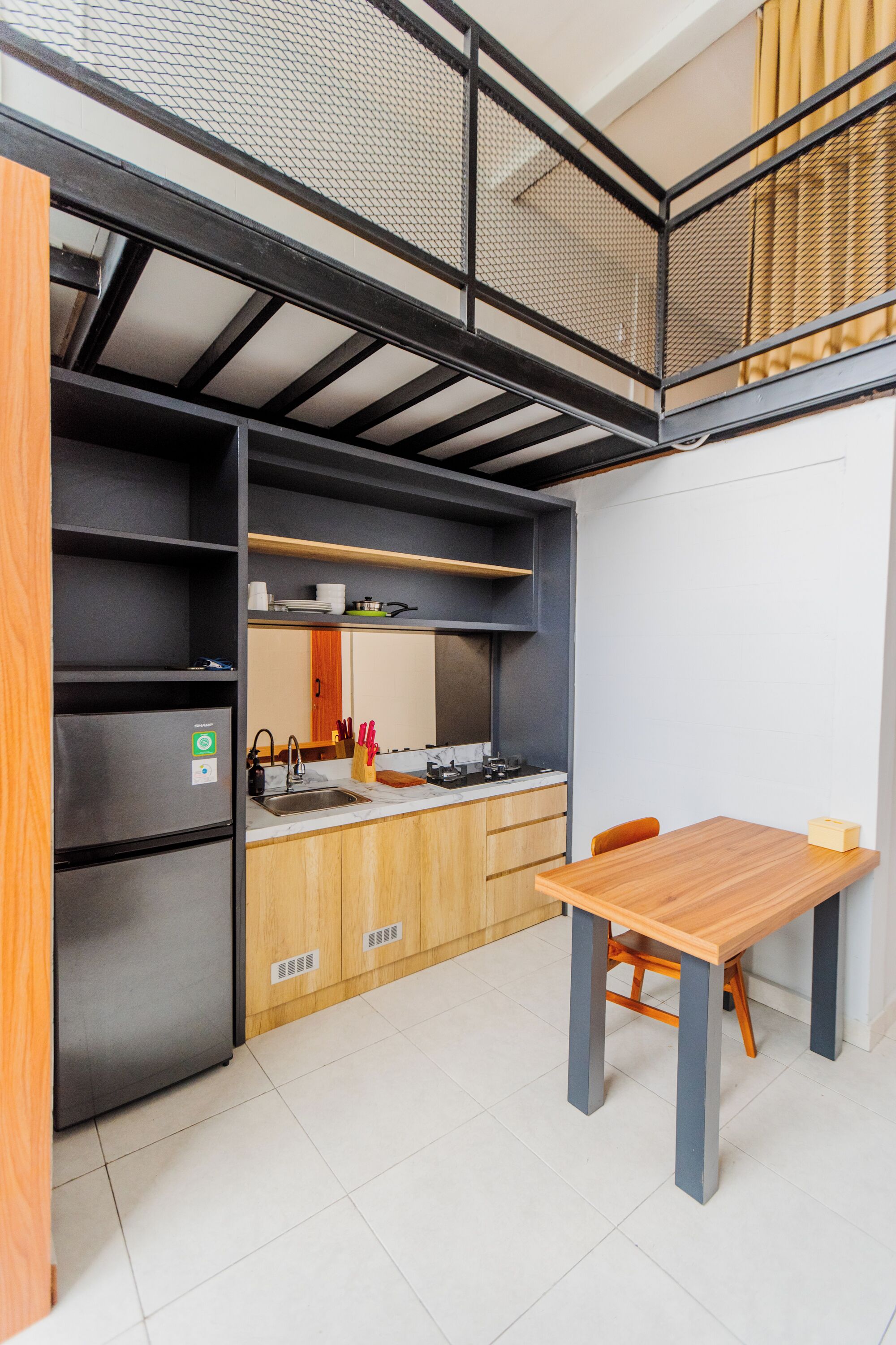 Una cocina compacta con refrigerador integrado, un lavamanos y una mesa de comedor de madera.