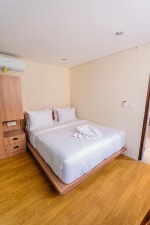 Un dormitorio con cama, piso de madera y armario.