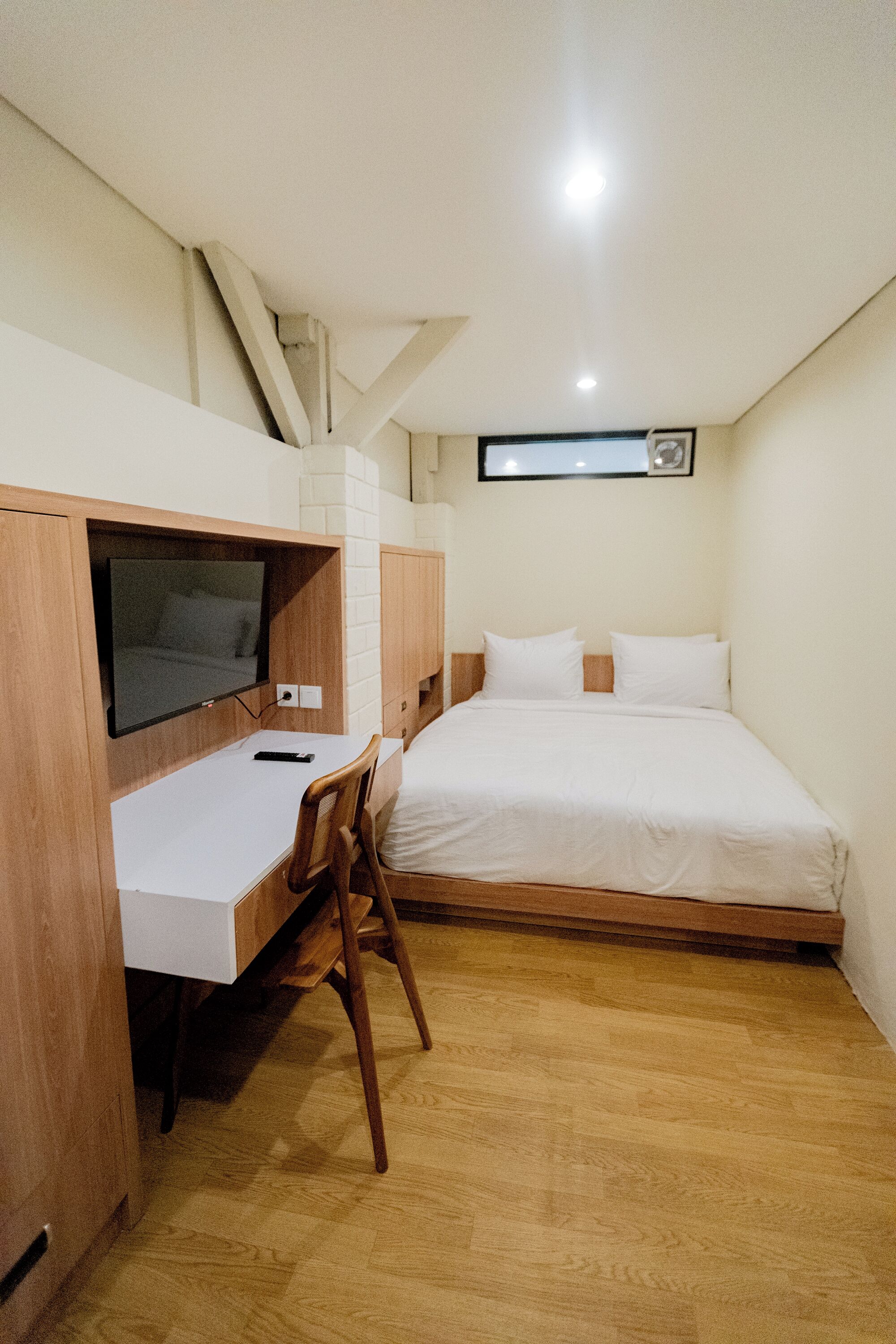 A bedroom with a bed, a desk, and a television.