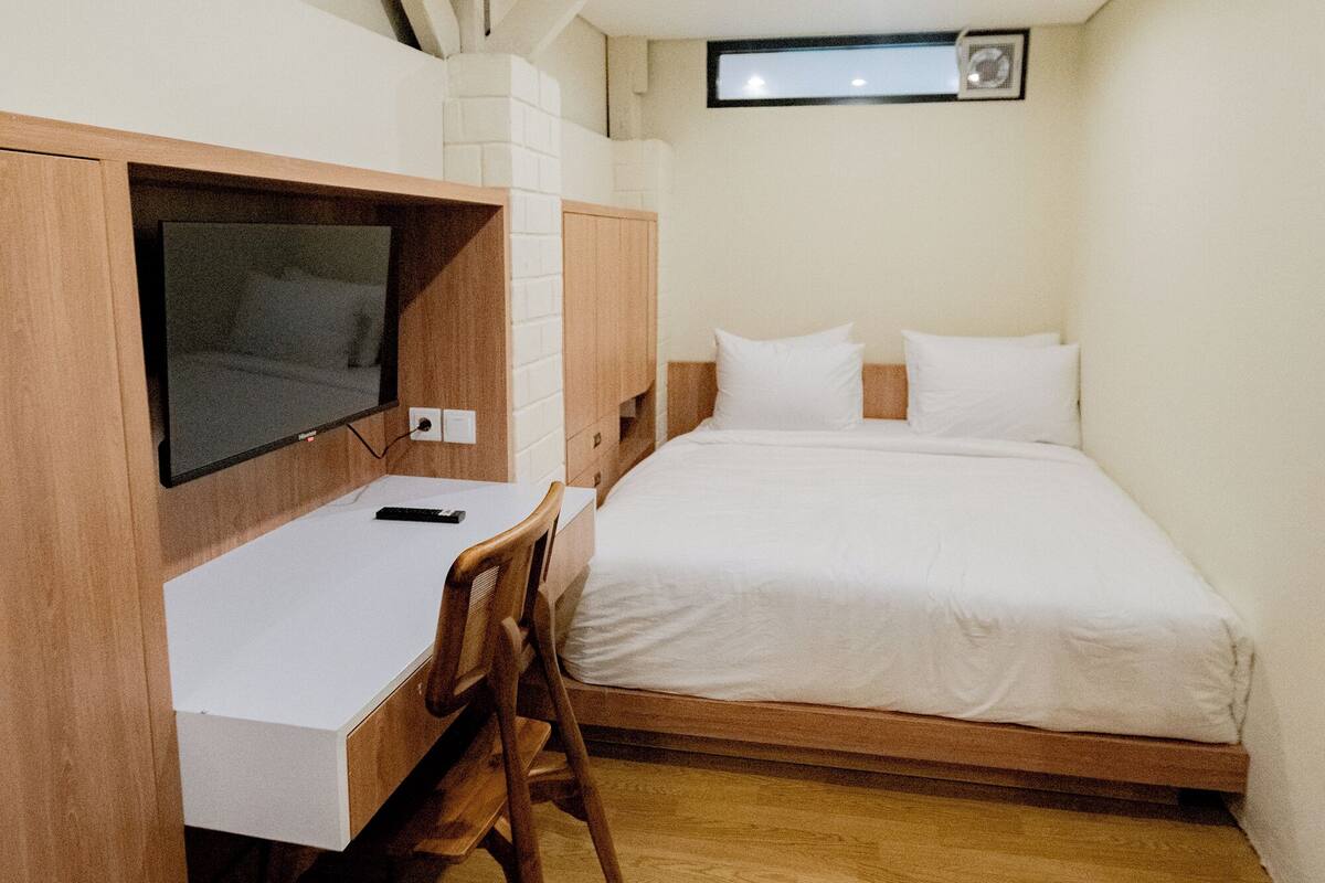 Un dormitorio con cama, escritorio y televisor.