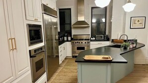 A kitchen with white cabinetry, stainless steel appliances, a black countertop island, and a backsplash. - Beautiful, spacious 5-bedroom house in downtown Oak Park very close to Chicago (Oak Park)