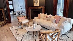 A living room with a white sofa, two armchairs, a coffee table, a fireplace, and a dining area in the background. - Beautiful, spacious 5-bedroom house in downtown Oak Park very close to Chicago (Oak Park)