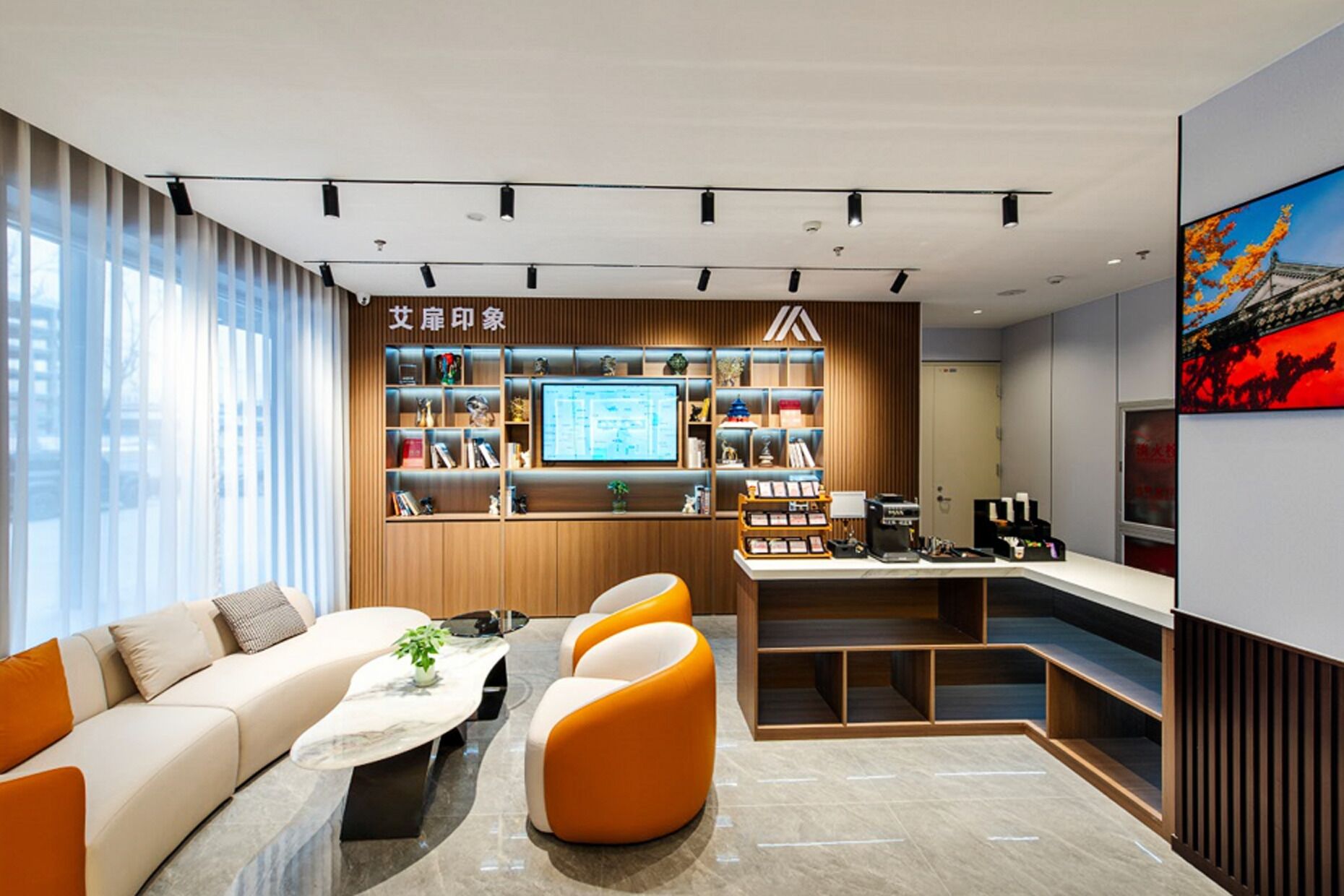 Un bureau moderne avec un canapé, des fauteuils orange, un bureau et une bibliothèque.