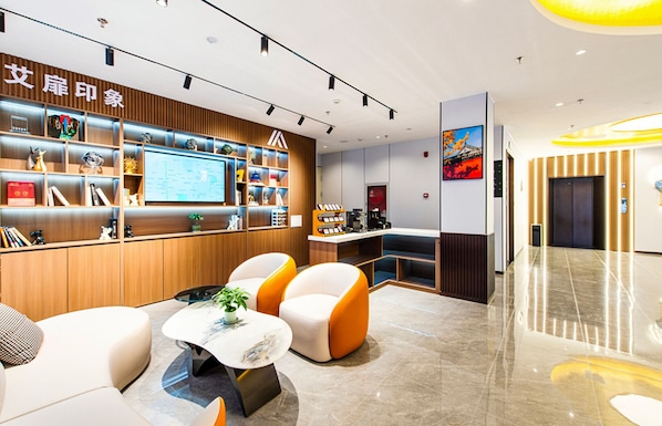 A modern hotel lobby with a reception desk, seating area, and a digital display. - Aifeel Hotel Beijing Capital Airport T3 (Shunyi)