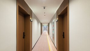 A long, narrow hallway with wooden doors on both sides, a central carpeted walkway, and a ceiling with recessed lighting. - Aifeel Hotel Beijing Capital Airport T3  (Shunyi)