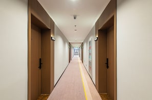 A hotel hallway with wooden doors, a carpeted floor, and a straight layout. - Aifeel Hotel Beijing Capital Airport T3 (Shunyi)