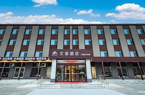 Et hotel med en moderne facade, mange vinduer og en rød løber ved indgangen.