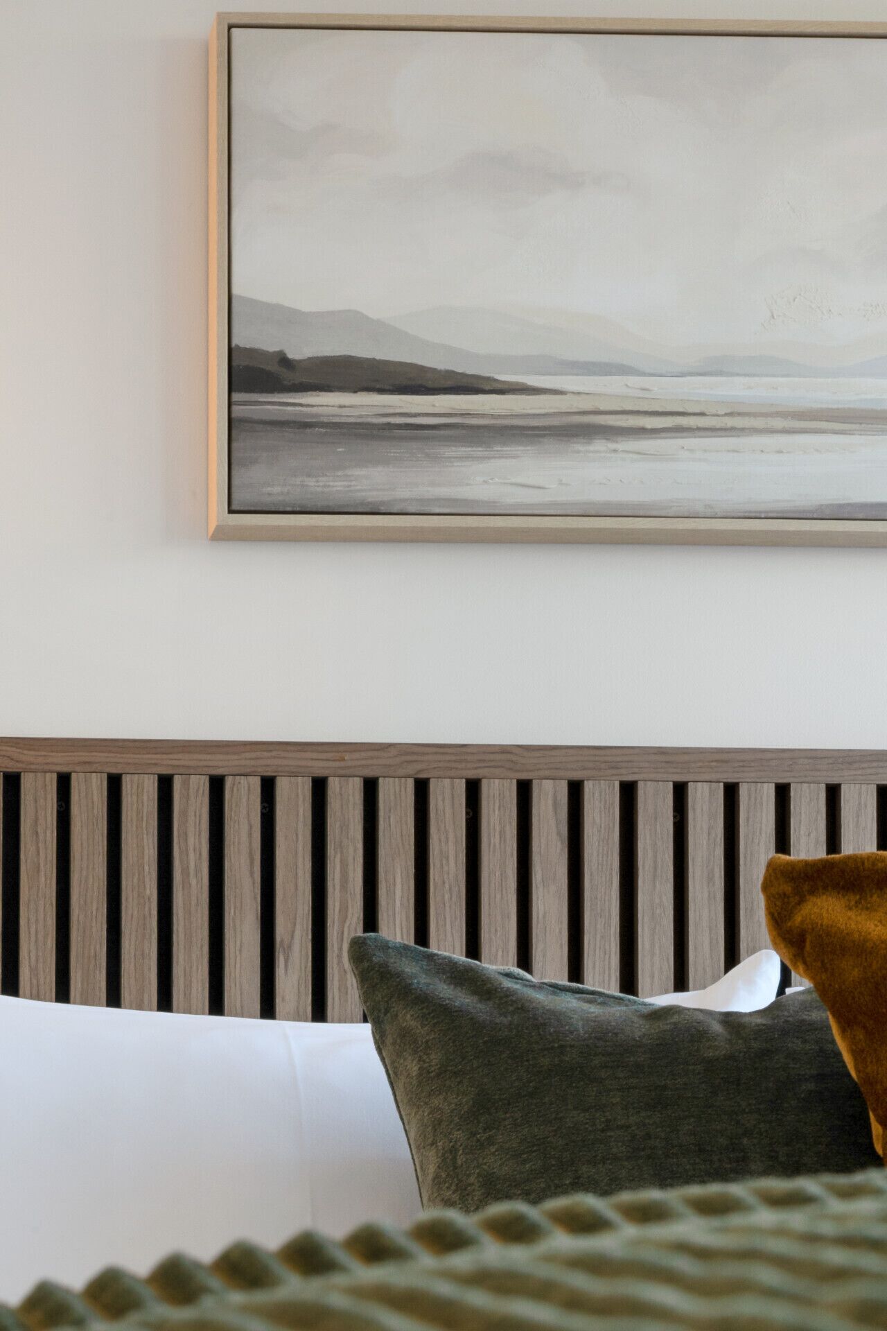 Ein Schlafzimmer mit einem Bett, einem Kopfteil und einem gerahmten Bild an der Wand.