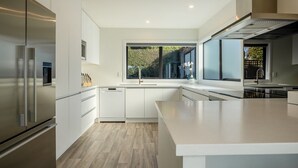 Eine moderne Küche mit weißen Schränken, Edelstahlgeräten und einem großen Fenster.
