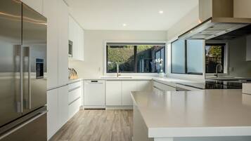 A modern kitchen with white cabinetry, stainless steel appliances, and a large window.