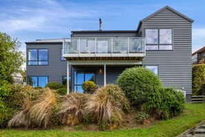 Une maison moderne à deux étages, dotée d’un balcon, d’une cheminée et d’un jardin bien entretenu.