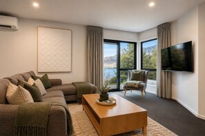 A modern living room with a sectional sofa, a single armchair, a coffee table, and a flat-screen TV. - The Gold Rise-| Two Living Areas-· Big Outdoors (Queenstown)