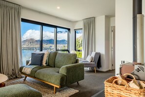 Ein modernes Wohnzimmer mit einer Couch, einem Sessel, einem Kamin und Blick auf die Berge.