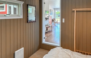 A bedroom with a bed, a radiator, a window, and a door leading to an outdoor area.