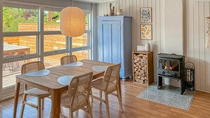 A dining area with a wooden table and chairs, a blue cabinet, and a wood-burning stove. - 2 bedroom stunning home in Vordingborg (Vordingborg)