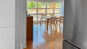 A modern kitchen with a wooden dining table and chairs, large windows, and a hanging light fixture. - 2 bedroom stunning home in Vordingborg (Vordingborg)