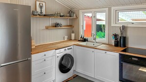 A compact kitchen with a built-in washing machine, a stainless steel refrigerator, and a window with a view of greenery. - 2 bedroom stunning home in Vordingborg (Vordingborg)