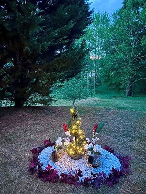 A Christmas tree in a garden with a circular arrangement of flowers and a birdcage. - D's Creekside NorthCarolinaHome Apartment A (Burlington)