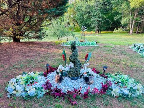 A garden with a central sculpture, surrounded by various plants and flowers.