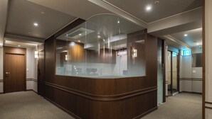 A reception desk with a glass partition, wooden paneling, and a carpeted floor. - ONJAE STAY SEONGSU (Seoul)