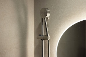 Una ducha con diseño moderno, un mando visible y un cabezal de ducha flexible.