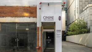 A building with a glass door entrance, a sign reading 'ONJAE STAY SEONGSU,' and a small sign with room numbers and names. - ONJAE STAY SEONGSU (Seoul)