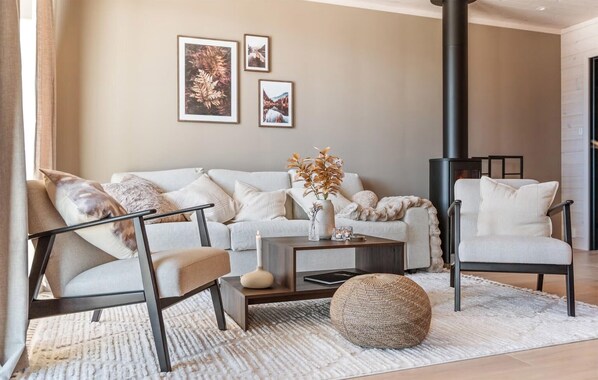 A living room with a sofa, chairs, a coffee table, a rug, and a fireplace.