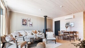 Ein modernes Wohnzimmer mit einer Couch, einem Couchtisch und Sesseln, einem Kamin und gerahmten Kunstwerken an der Wand.