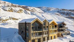 Ein modernes Skiresort-Gebäude mit großen Fenstern und Balkonen, umgeben von verschneiten Bergen.