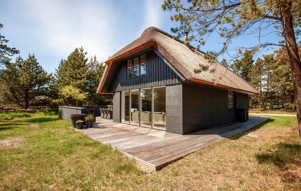 A modern house with a thatched roof, large windows, and a wooden deck. - Lovely home in Blåvand with WiFi (Blåvand)