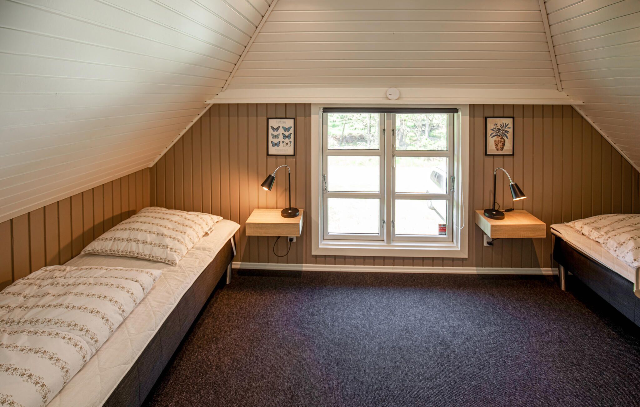 A bedroom with two beds, a window with a view, and two bedside lamps.