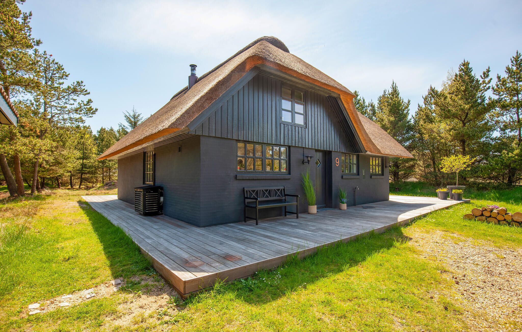 A cabin with a wooden deck, a bench, and a potted plant.