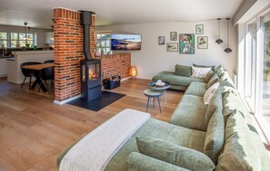 A cozy living room with a fireplace, a sofa, a dining area, and artwork on the walls. - Lovely home in Blåvand with WiFi (Blåvand)