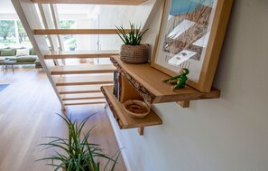 A modern interior with a wooden staircase, a shelf with a plant and a small figurine, and a framed picture on the wall. - Lovely home in Blåvand with WiFi (Blåvand)