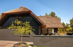 A modern house with a thatched roof, a wooden deck, and a small tree. - Lovely home in Blåvand with WiFi (Blåvand)