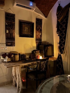 Une pièce comprenant un bureau, une chaise, une table, un appareil de climatisation et un tableau encadré accroché au mur.