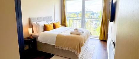 Una camera d'albergo con un letto, un comodino, una lampada e vista sulla città dalla finestra.