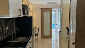 Eine moderne Küche mit schwarzem Arbeitsplatz, Spüle aus Edelstahl und Glastür zum Balkon.