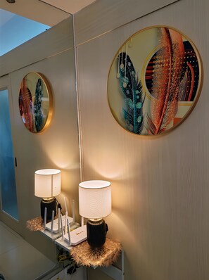 A bathroom with a mirror, two wall-mounted lamps, and a decorative wall piece. - Comfystay Manila (Pasay City)