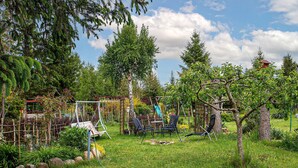 Ein Garten mit Bäumen, einer Schaukel und einem kleinen Gartenhaus.
