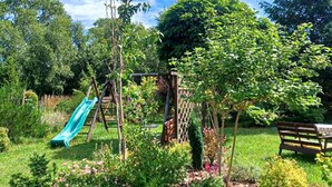 Ein Garten mit einer Holzbank, einer Kletterkonstruktion und einer Rutsche.