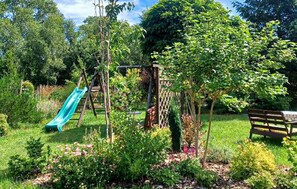 Ein Garten mit einer Holzbank, einer Kletterkonstruktion und einer Rutsche.