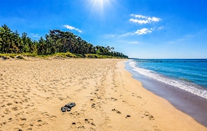 A beach with footprints and a pair of sandals, a clear sky, and a distant pier. - Awesome home in Kopan with heated swimming pool (Kopan)
