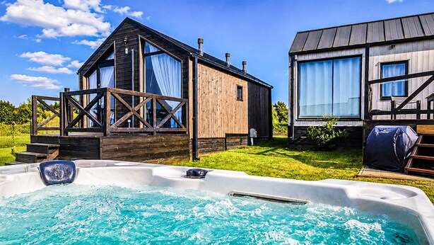 Una cabaña de madera con jacuzzi, terraza y un gran ventanal.