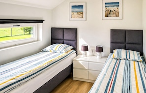 A twin bedroom with two beds, a window, a bedside table with lamps, and two framed pictures on the wall. - Awesome home in Kopan with heated swimming pool (Kopan)