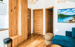 Ein Zimmer mit Holztüren, einem blauen Sofa, einem Gemälde eines Sees und einem Mülleimer.