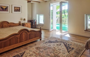 Une chambre avec un lit en bois, un bureau, une chaise et une grande fenêtre.