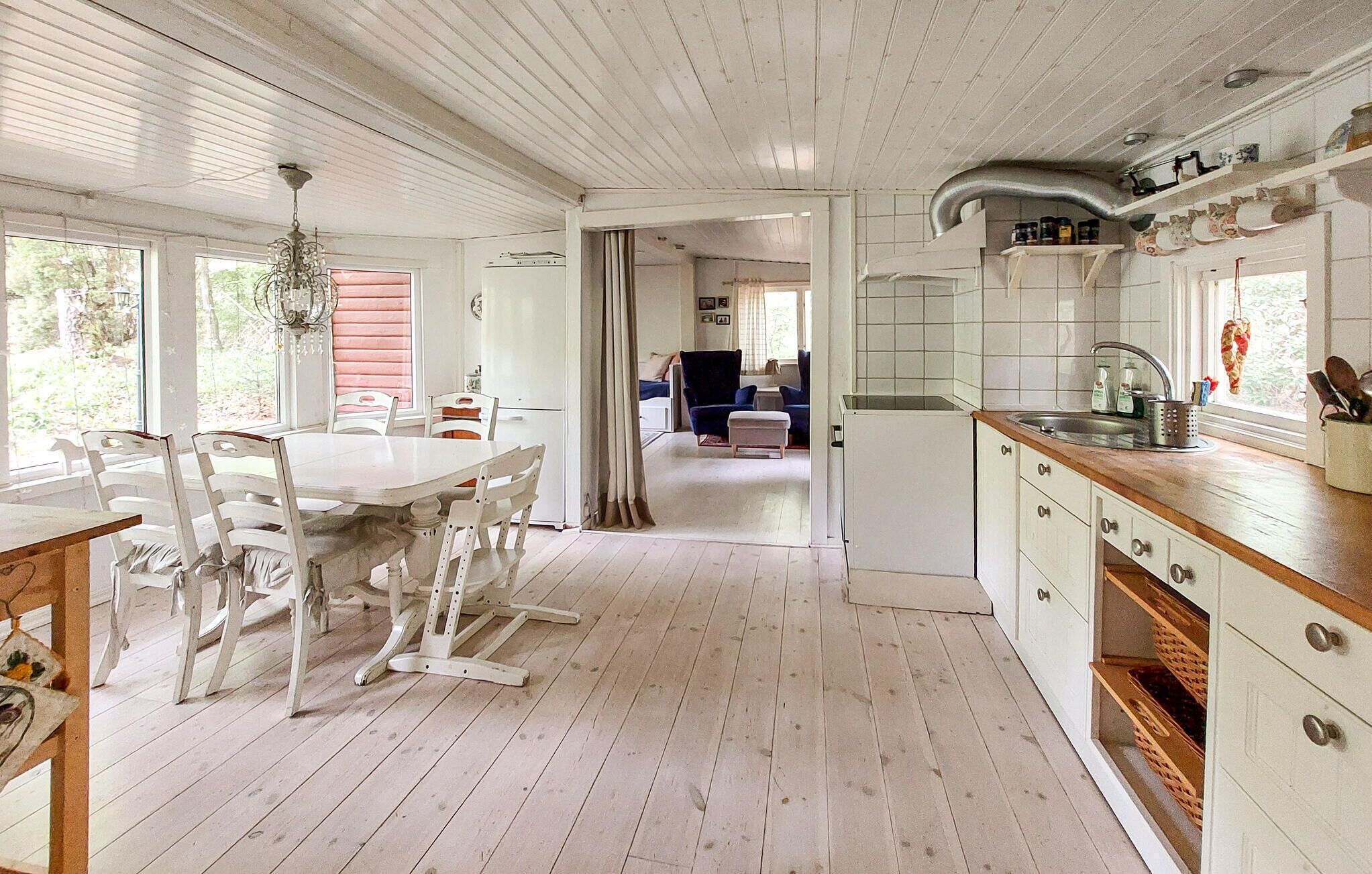 A spacious kitchen with a dining area, wooden floors, and a view into the living room.