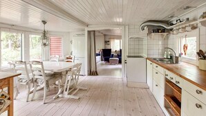 A spacious kitchen with a dining area, wooden floors, and a view into the living room. - 2 bedroom cozy home in Sösdala (Sösdala)
