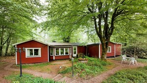 A red wooden cabin with a chimney, a porch, and a garden area with a bench. - 2 bedroom cozy home in Sösdala (Sösdala)